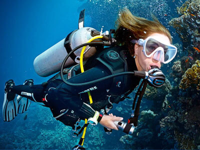 サンゴ礁のポイントを潜る女性ダイバー