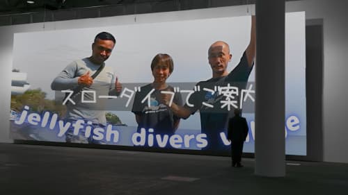 壁一面のバリ島くらげ村の広告を見てる男性