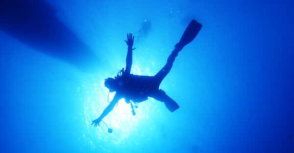 バリ島ダイビングで太陽バックに手足を大の字に広げるダイバー
