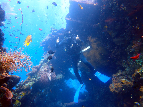 バリ島ダイビングで沈船をバックに記念撮影するダイバー