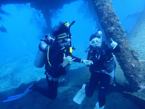 バリ島トランベンの沈船の貨物室内で記念撮影するカップルダイバー