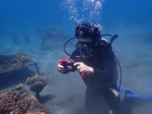 カメラを構えて水中撮影を楽しむ男性ダイバー