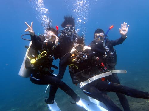 バリ島体験ダイビングで水中で記念の集合写真を撮るガイドと3名のダイバー