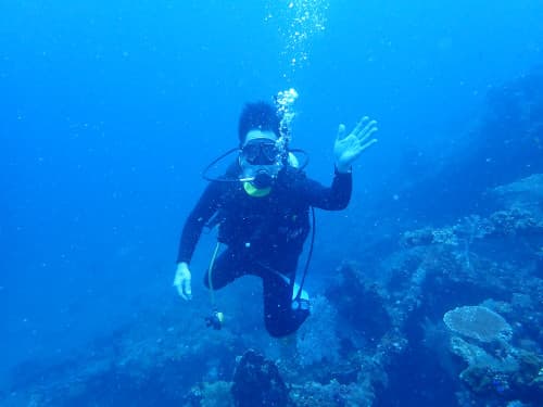 水中で左手を上げて記念撮影するダイバー