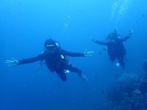 水中で両手を広げて記念撮影する２人の女性ダイバー