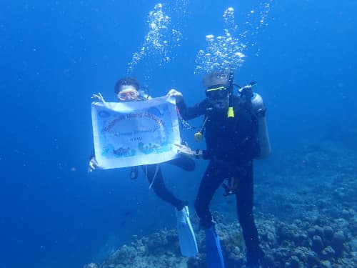 水中で誕生日おめでとうフラッグを持って記念撮影する2名のダイバー