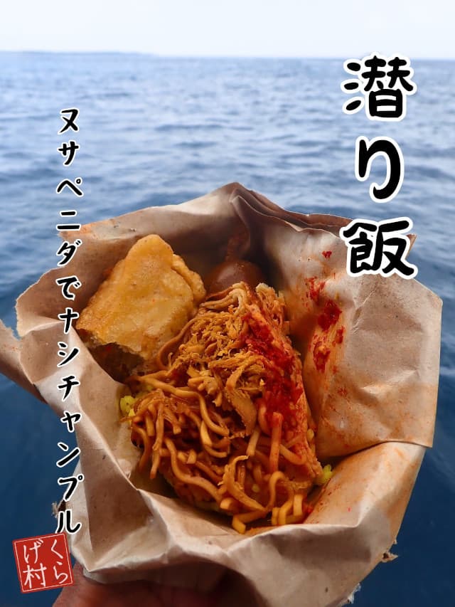 潜り飯、海をバックにナシチャンプルのブンクスを手に持っている画像