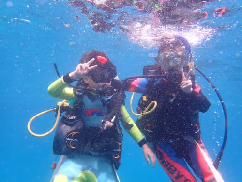 水中でピースしている2人の子供ダイバーの海景