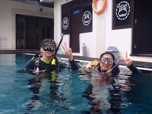 プールの水面に顔を出している2名のダイバー