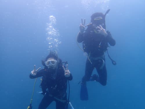 海中でピースサインをしている2名のダイバー