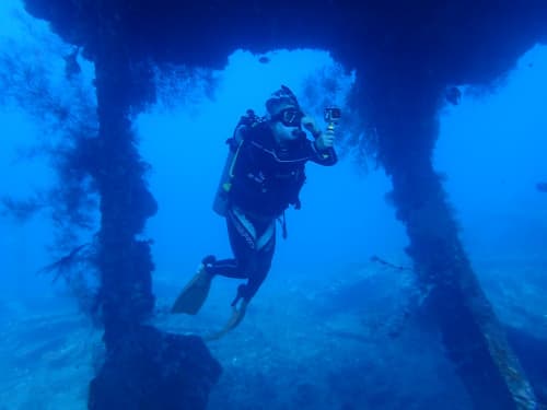 沈船内の柱のある部屋でアクションカメラで撮影しているダイバーの海景