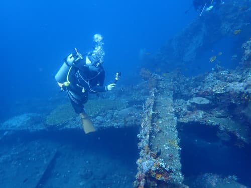 沈船の大きな長い柱の横をアクションカメラで撮影しながら泳ぐダイバーの海景