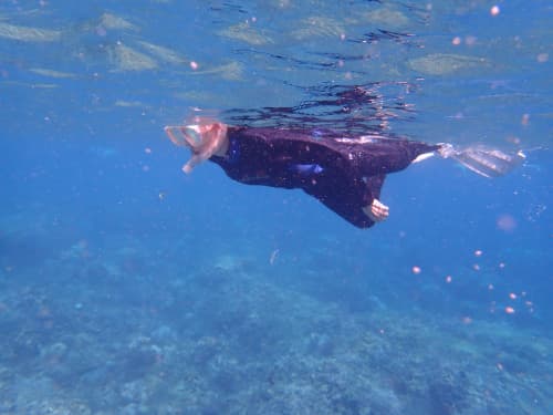 バリ島のサンゴ礁のシュノーケリングポイントで水面を泳いでいる女性シュノーケラー
