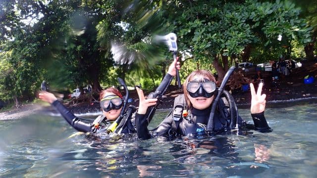 バリ島トランベンの水面でピースサインをする女性ダイバー、バリ島くらげ村は安全の為の少人数制でご案内