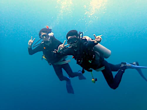 海中でピースしている2名の学生ダイバーの海景
