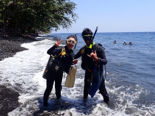 バリ島トランベンのビーチでダイビング前の記念撮影をしているカップルダイバー