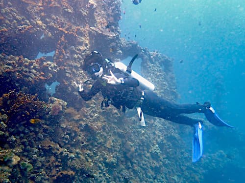 沈船ポイントに潜りピースサインで記念撮影しているダイバーの海景