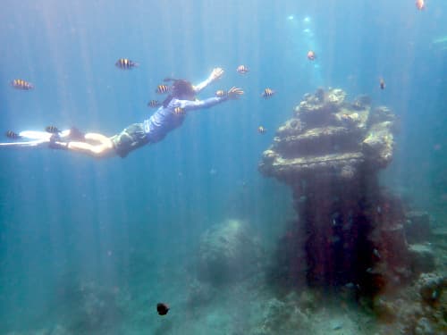 アメッドの浅瀬の海に沈められた石灯篭に向かって潜るシュノーケリング女子