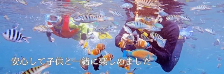 水面でたくさんのお魚を見ながらバリ島シュノーケリングを楽しむ父と小さな子供