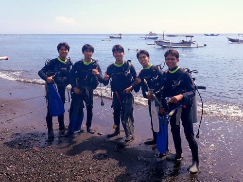 バリ島アメッドのビーチで記念撮影する5人の男子学生ダイバー