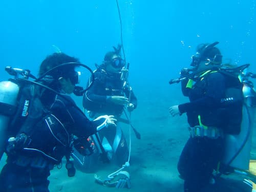 バリ島くらげ村のSSI OWダイバーコースの水中スキル「オクトパスによる空気供給浮上」を頑張る二人の女子大生ダイバーをインストラクター
