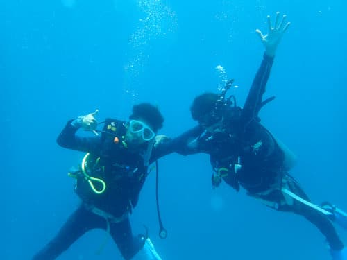 水中で楽しそうにポーズを取る2名の男子学生ダイバー