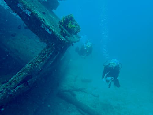バリ島パダンバイのダイビングポイント「タンジュンジュプン」に沈んでいる沈船の横を泳ぐ２名のダイバー
