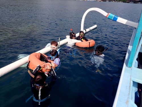 バリ島パダンバイのタンジュンジュプンの穏やかな水面でシュノーケリングをする友人ご家族とくらげ村シュノーケリングインストラクター