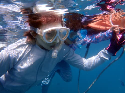 バリ島パダンバイのブルーラクーンでフロートに捕まりながら安心してシュノーケリングを楽しむ娘と母親