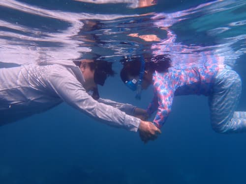 娘の手を支えながらバリ島シュノーケリングを楽しむ父親