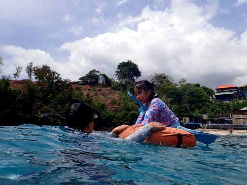 バリ島パダンバイのブルーラグーンでフロートに乗った娘とそれを支えて楽しむ父親