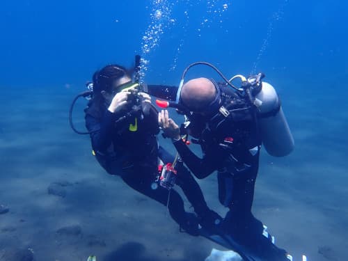 日本人インストラクターが優しく体験ダイバーのフォローをしている