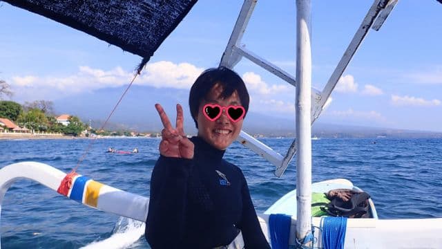 バリ島の海を背景に笑顔で座るダイバーのお客様