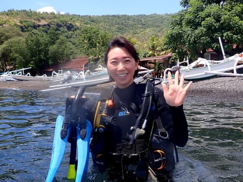 ビーチダイブでこれからエントリーする笑顔の女性ダイバー