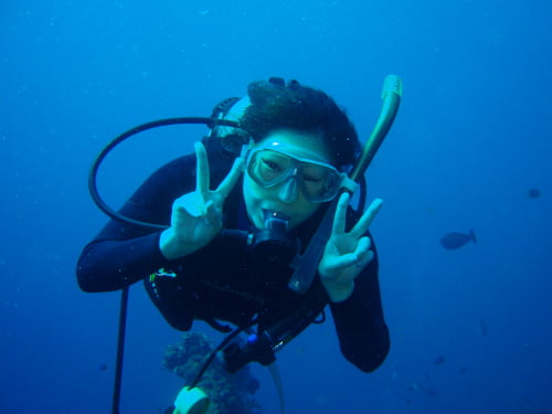 バリ島くらげ村のスローダイブで安心してダイビングを楽しんでいるダブルピースの女性ダイバー