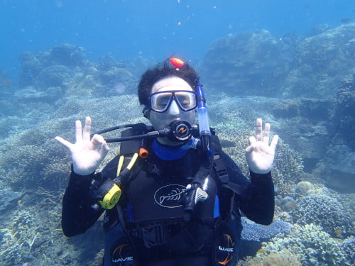 バリ島の海をリラックスして楽しむダブルOKサインの男性ダイバー