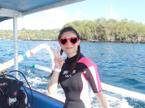 バリ島パダンバイのジュクンの上でピースサインする女性ダイバー