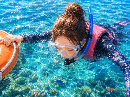 バリ島の海で、片手でフロートに掴まりながら顔を水につけてシュノーケリングをする女性