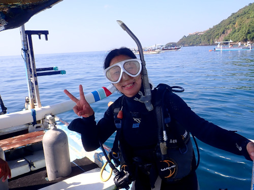 バリ島で初めての体験ダイビングを楽しむ初心者ゲストがボート上で笑顔のピースサイン
