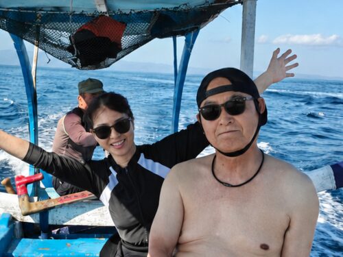 バリ島の海でジュクンに乗り、笑顔を見せるダイビング参加のご夫婦