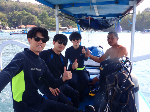 バリ島で体験ダイビングを楽しむ大学時代の友人3人がボート上で記念撮影する様子